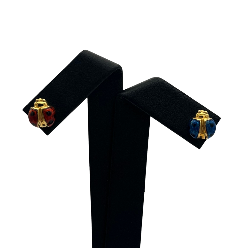 Pair of ladybug earrings on a black stand with a white background