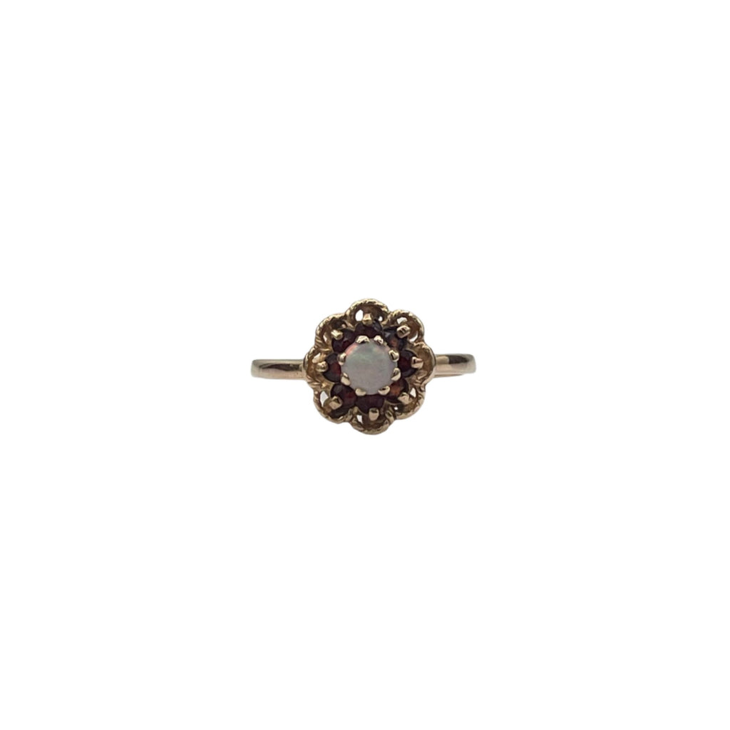 Lovely 14K yellow gold ring. A beautiful opal is set in the heart of the flower and 8 small garnets serve as petals in an openwork decor.